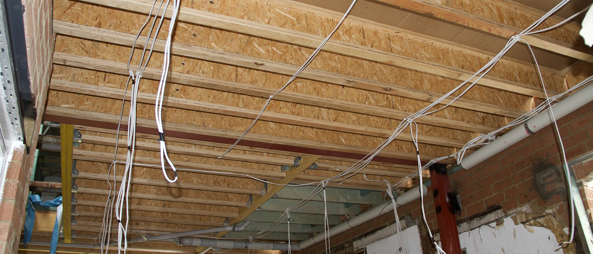 Cabling run through exposed joists and brickwork during rough-in on the Annandale rebuild, every circuit set before the ceiling closes.